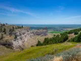 Panoramic view across Scotts Bluff National Monument and surrounding green and rugged landscape on clear day.