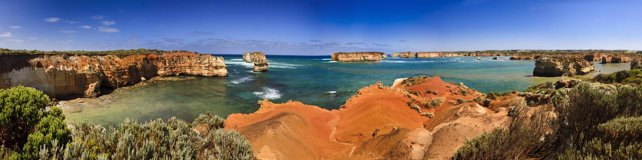 Panoramic view of cliffs around a wide bay with calm turquoise ocean 