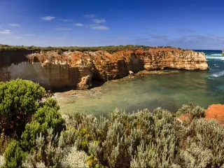 Panoramic view of cliffs around a wide bay with calm turquoise ocean 