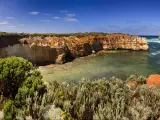 Panoramic view of cliffs around a wide bay with calm turquoise ocean 