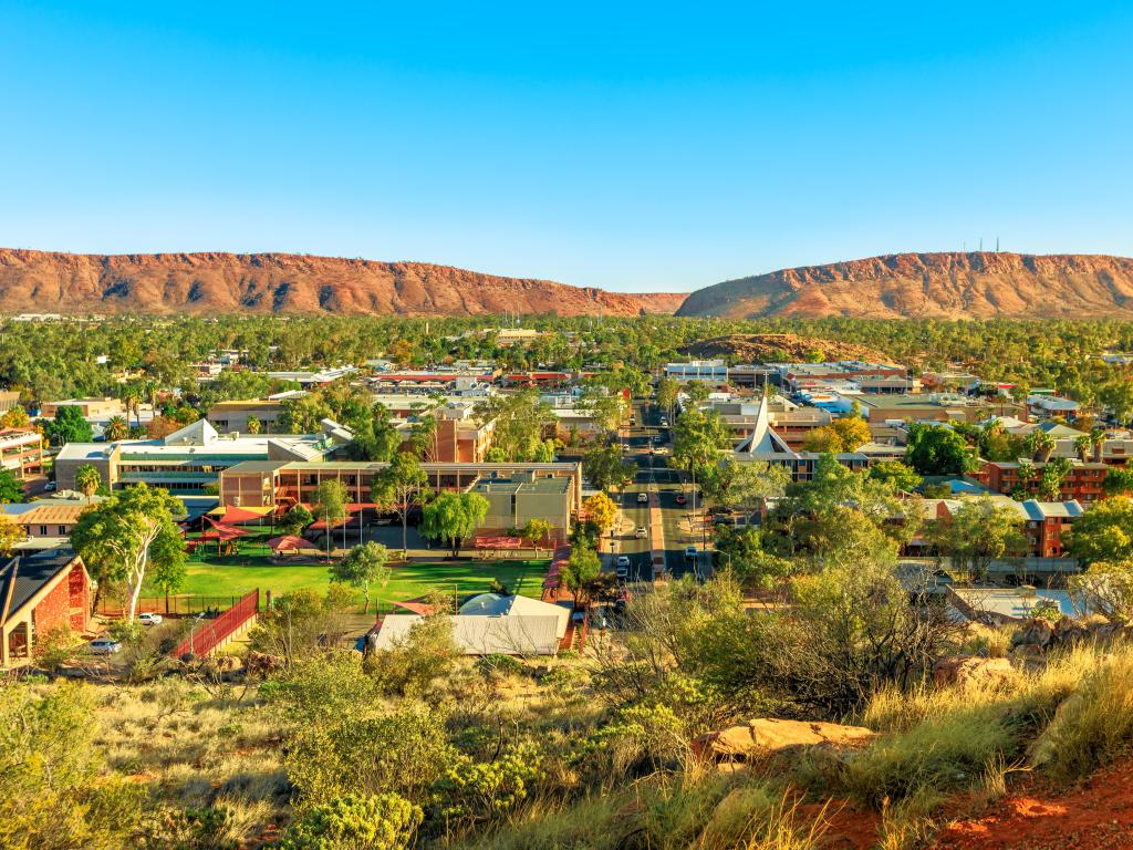 Alice Springs, Australia with an aerial view of Alice Springs skyline in Australia from Anzac Hill Memorial lookout with main buildings of Alice Springs city downtown. Red Centre desert with Macdonnell ranges of Northern Territory.