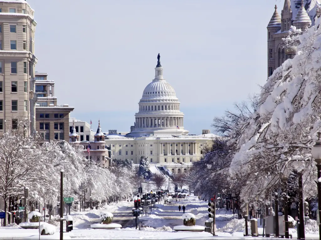 A snowy winter scene in Washington D.C. with a street leading to the U.S. Capitol