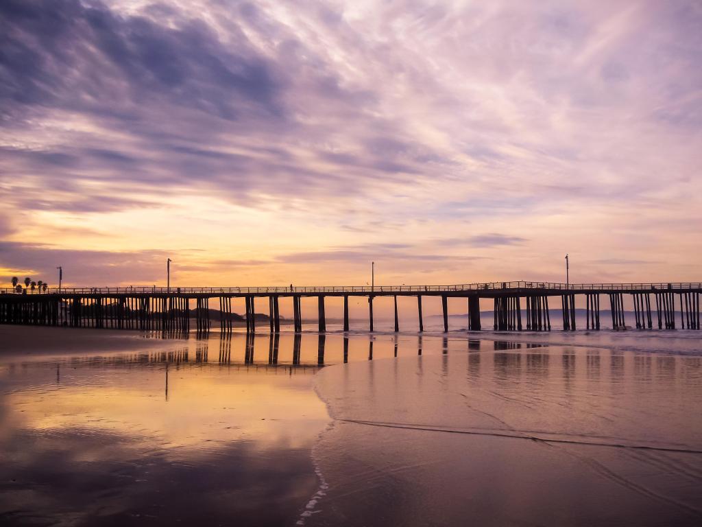 Pismo Beach, California, USA with a pink sunrise and wooden jetty in the distance. 