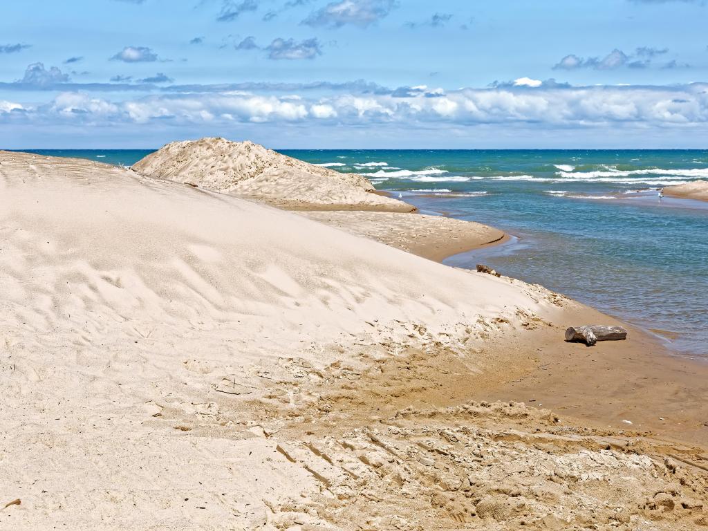 Indiana Dunes National Park, Lake Michigan with white golden sand and the water sweeping the dunes on a sunny day.