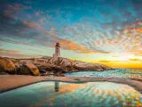 Halifax, Nova Scotia, Canada taken at Peggy's Cove Lighthouse at sunset with a ocean view landscape and water reflecting in the foreground.