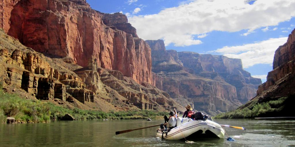 A raft boat floats down the Colorado River in the Grand Canyon