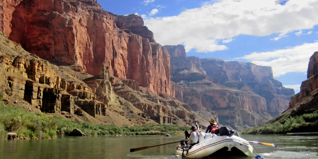 A raft boat floats down the Colorado River in the Grand Canyon