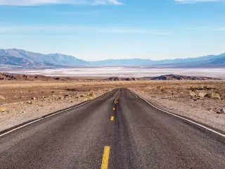 Road leading into Death Valley with blue skies ahead