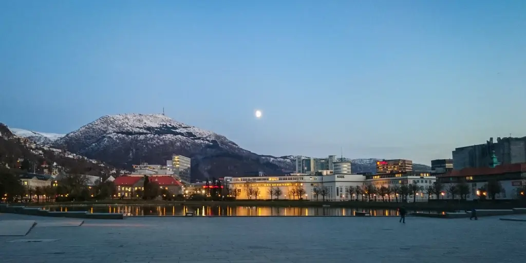 The moon sets over the city of Bergen and Mount Ulriken in Norway
