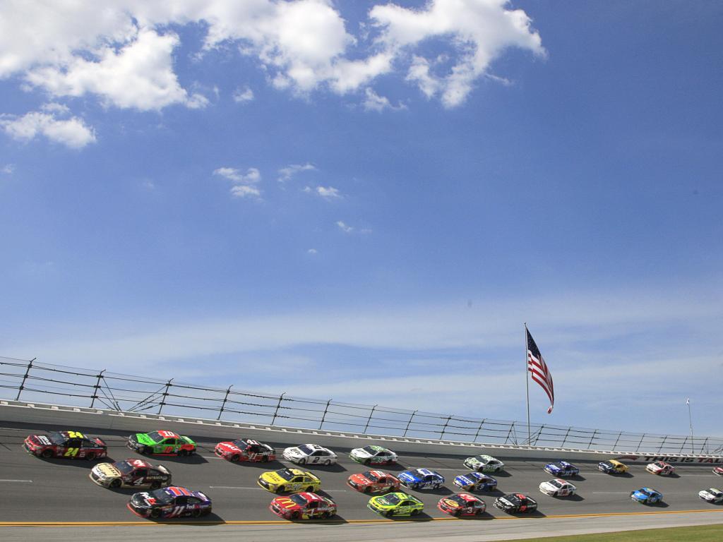 Cars whizz around the track at Talladega Super Speedway, Alabama, with the US Flag flying above