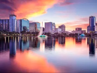 Orlando, Florida downtown city skyline at sunset with the tall buildings reflecting in the waters edge.