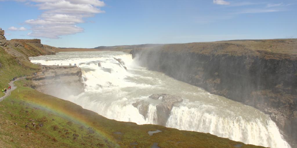A rainbow forms over Gulfoss waterfull on a sunny day