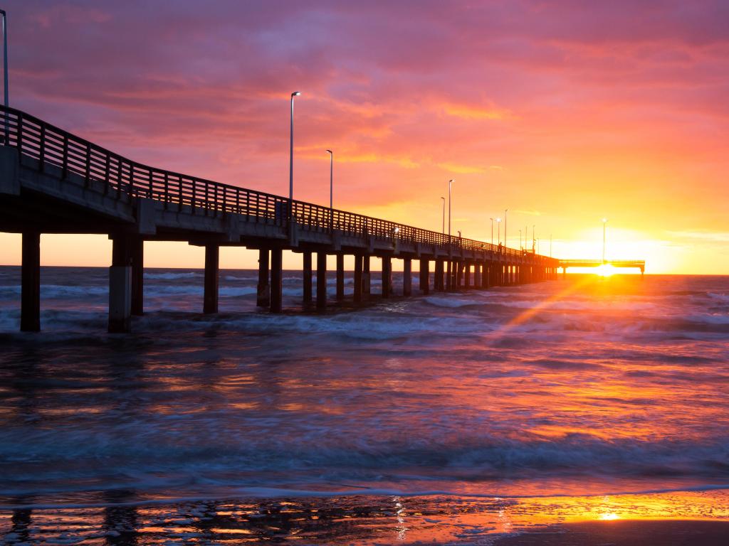 Sun setting over the sea with a pier 