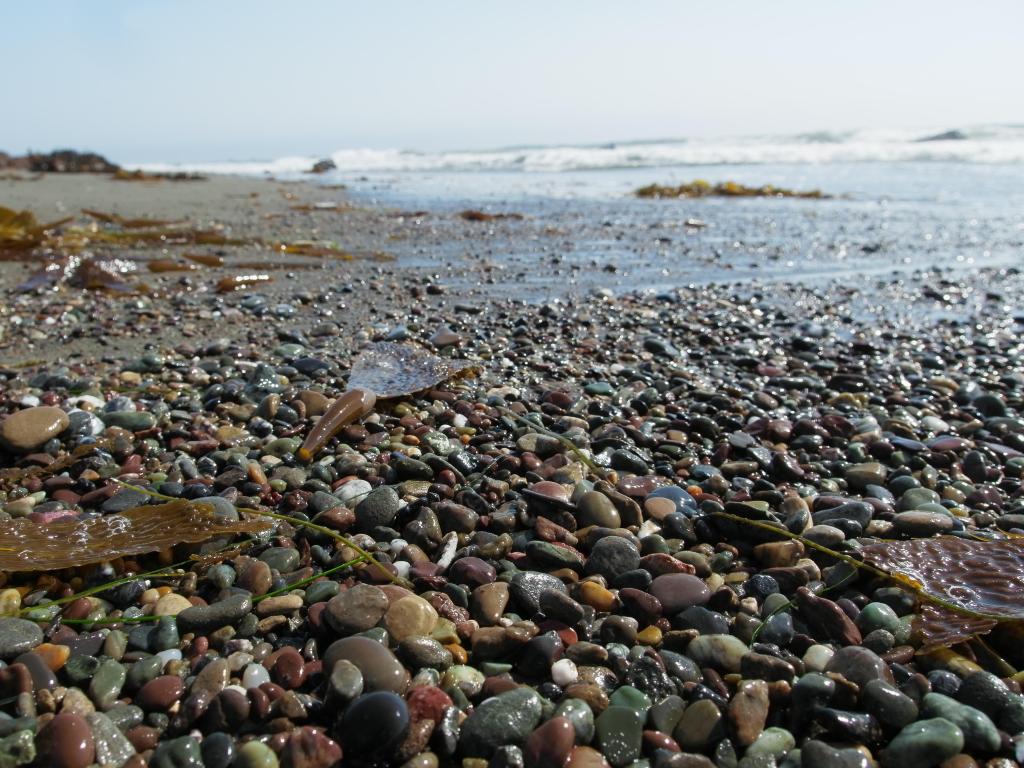 Close up of colorful pebbles at the beach and incoming waves