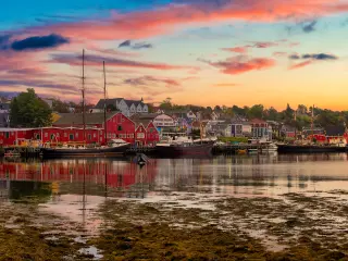 Panoramic view of red waterfront port buildings reflected in calm water in silver sunrise light