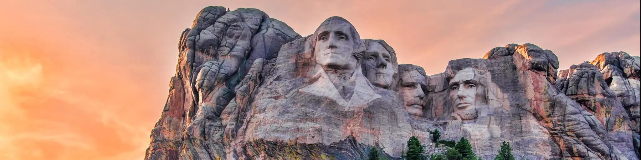 Mount Rushmore National Memorial, Black Hills region of South Dakota, USA with the famous four heads of four previous presidents carved into the granite cliffs and a red sky above.