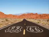 Route 66 pavement sign with Mojave desert red rock mountains.