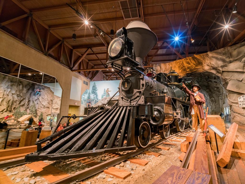 An old train at the museum with a sculpture of a man next to it