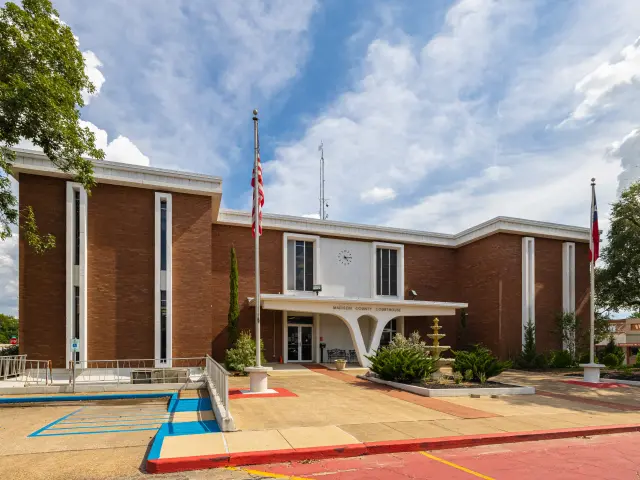 The exterior of red brick Madison County Courthouse at Madisonville, Texas