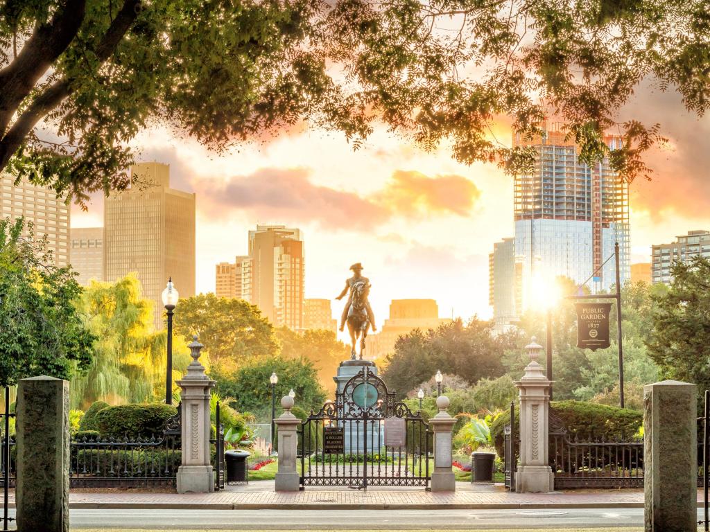 Statue of man on horse in public square illuminated in bright early morning light with buildings behind