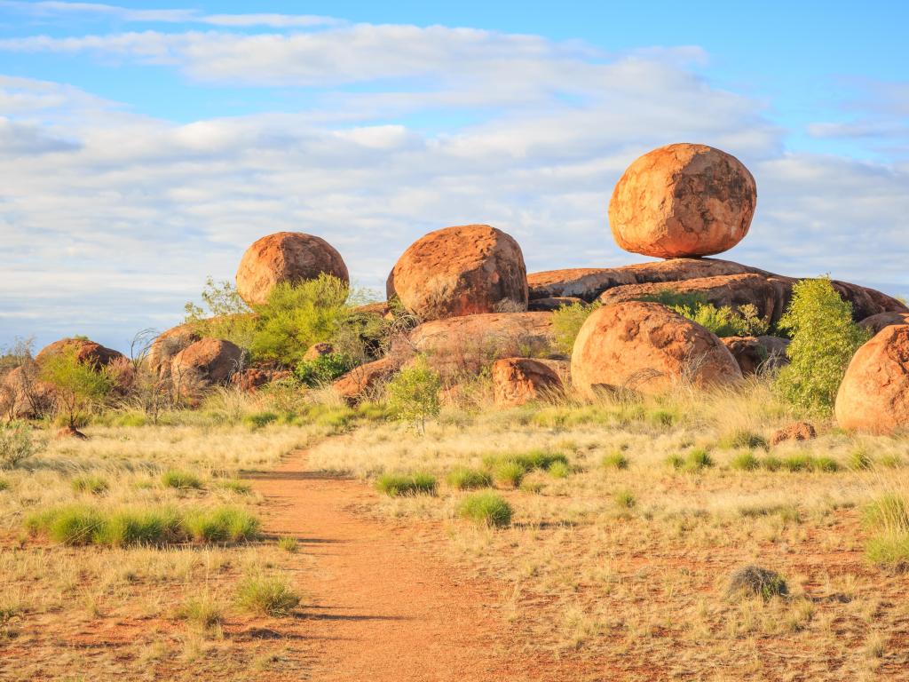 Devil's Marbles/Karlu Karlu, Australia with one main boulder and others sit upon a natural rock formation on a sunny day.