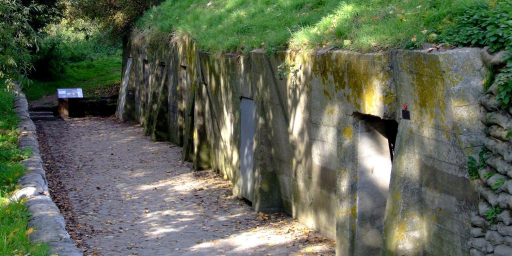 The concrete bunker of Essex Farm Dressing Station, Belgium, covered in grass with the sun peaking through