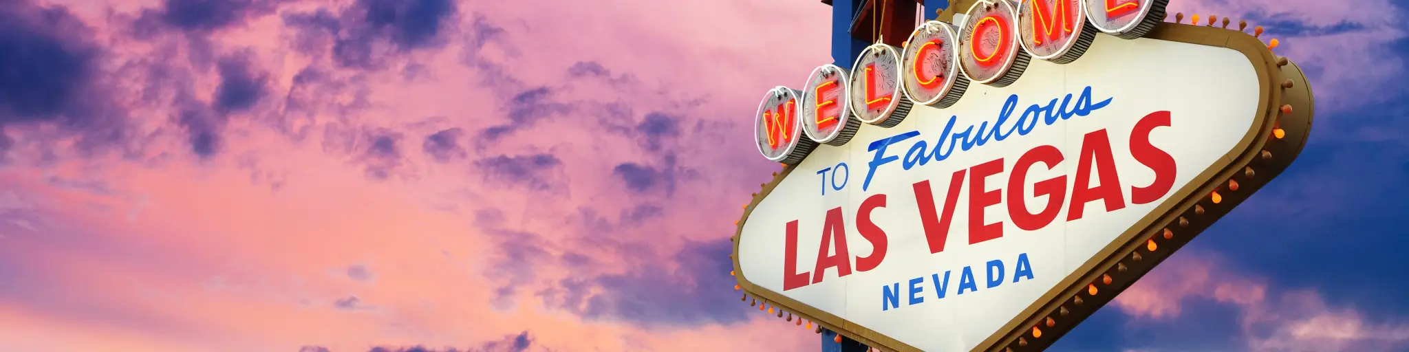 Famous "Welcome To Las Vegas" neon sign with a purple and pink sunset in the background