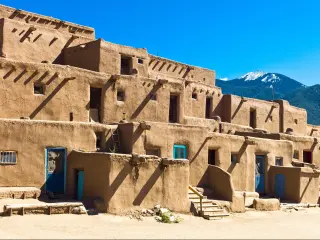 Taos Pueblo, New Mexico, USA on a sunny day with a mountain in the distance.