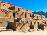 Taos Pueblo, New Mexico, USA on a sunny day with a mountain in the distance.