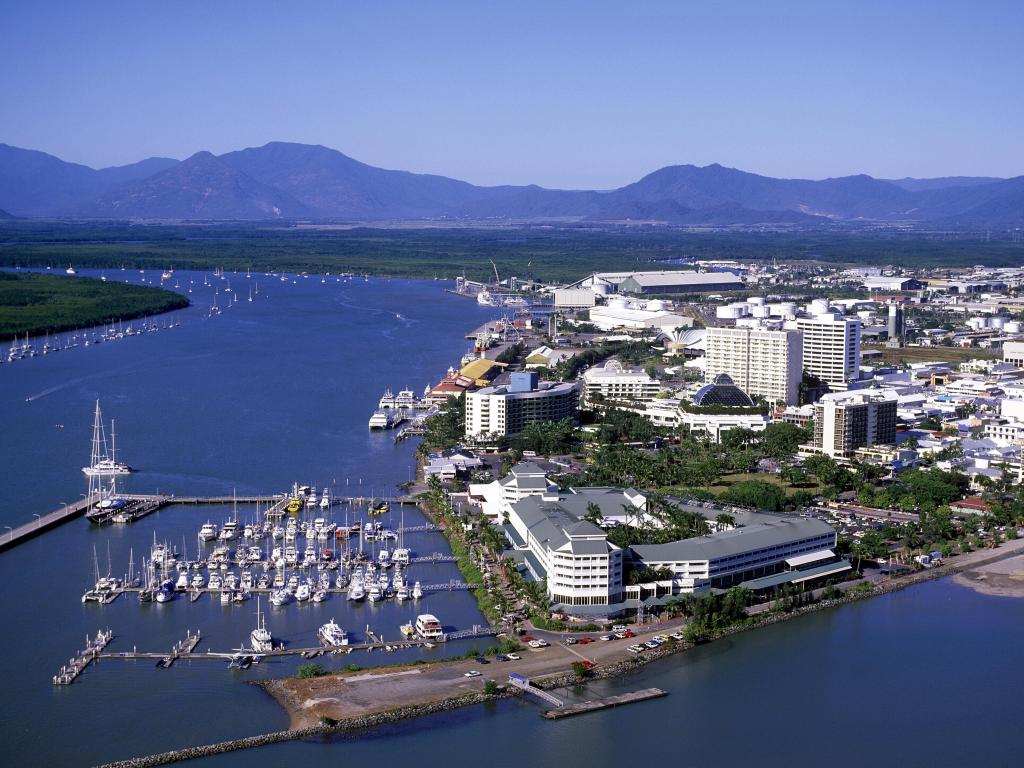 View of Cairns from the air with deep blue river and ocean, boats in a harbour and white buildings