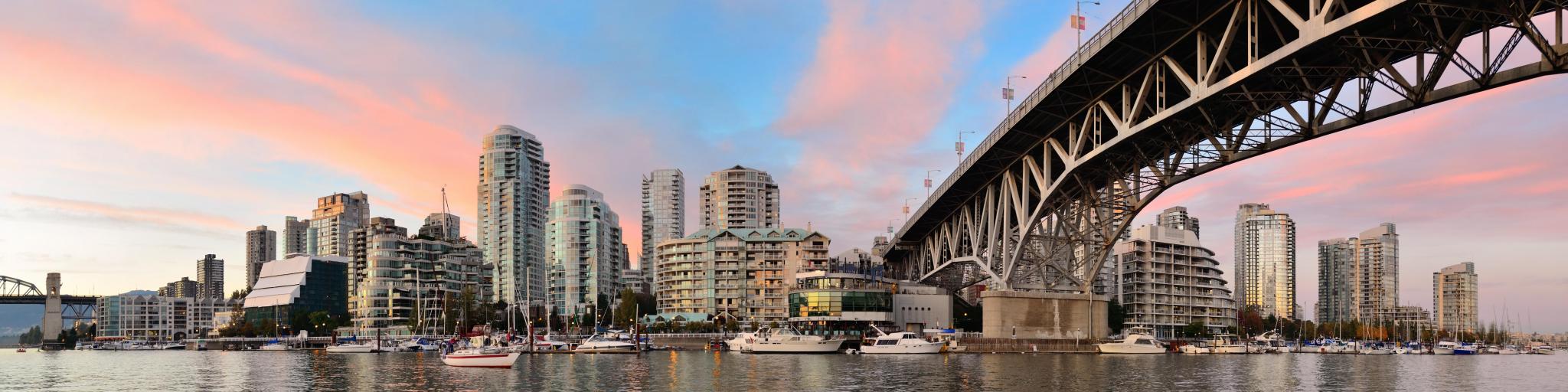 Vancouver False Creek panorama at sunset with bridge and boat. The photo is taken on a rather clear day and shows Vancouver's silhouette.
