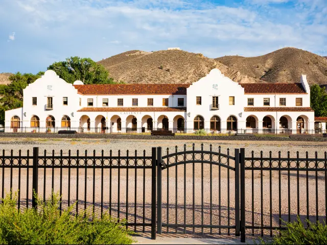 The Historic Railroad Station in Caliente, Nevada with hills in the background and and iron fence at the front