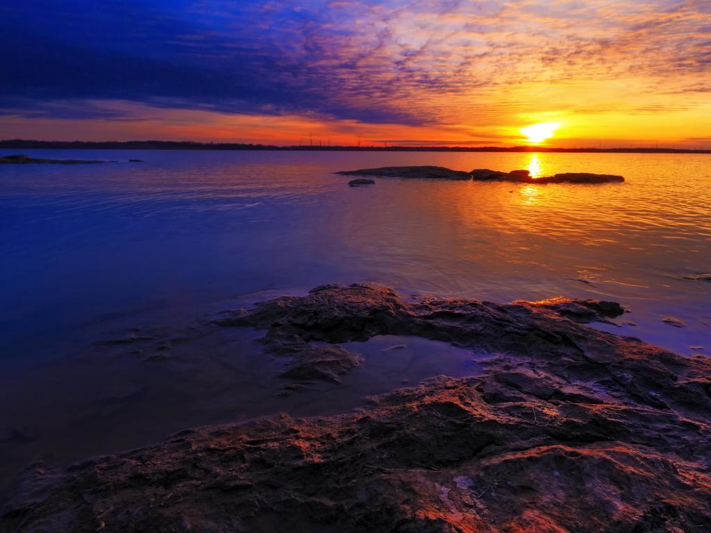 Sunset of Truman Lake, located as part of the Lake of the Ozarks in Missouri, USA with a colorful sky and rocky shoreline.