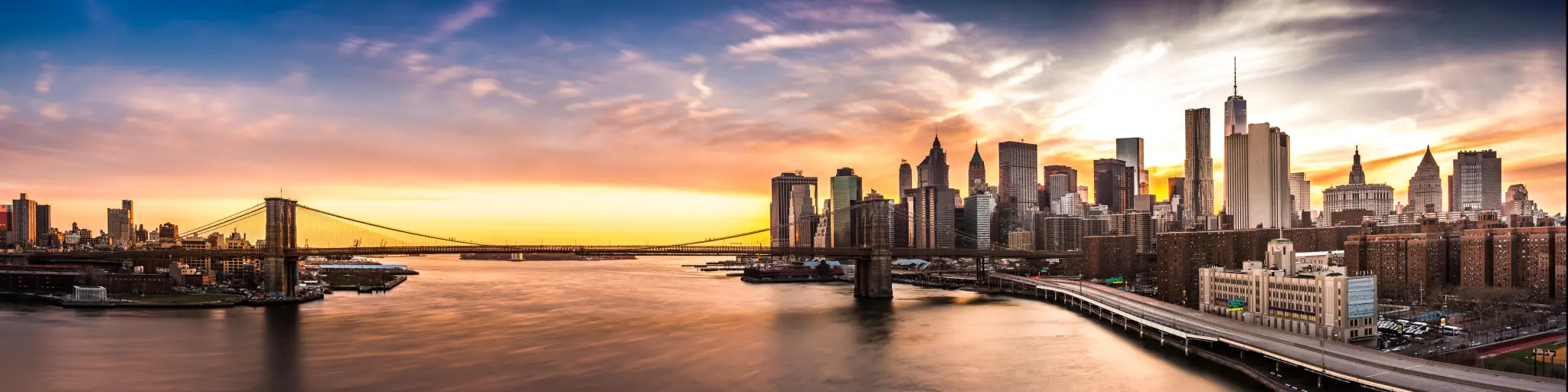 New York City Skyline at sunset with Brooklyn Bridge and Wall Street skyscrapers 