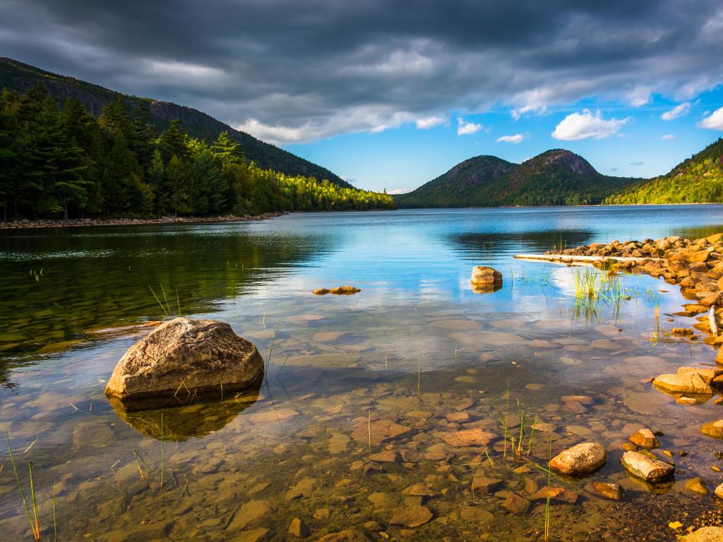 Acadia National Park, Maine, USA taken at Jordan Pond with view of the Bubbles, calm water, mountains in the distance and a cloudy sky. 
