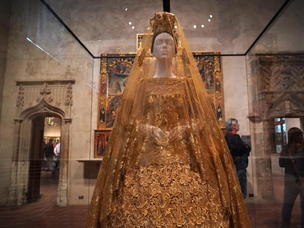 Display of elaborate gold gown at Fashion and the Catholic Imagination at Met museum, blending fashion and medieval art