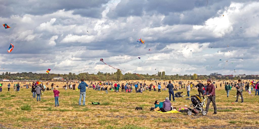 People flying kites and walking around the field at Tempelhof abandoned airport in Berlin