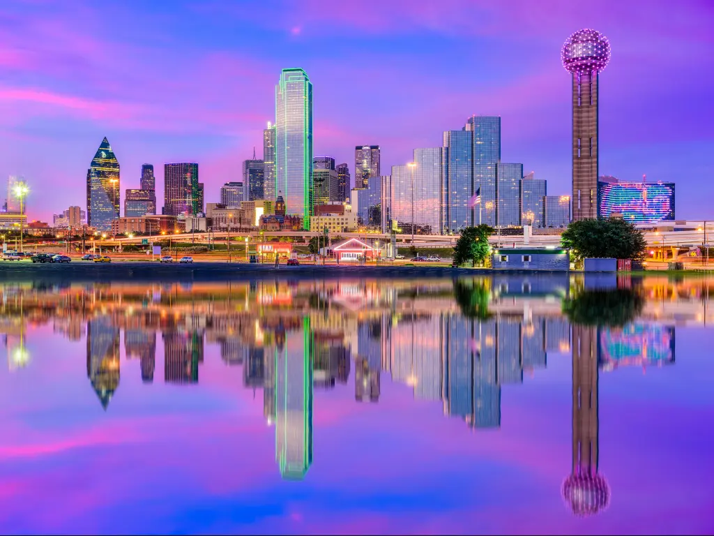 Dallas, Texas, USA downtown city skyline at night with the skyscrapers reflecting in the water in the foreground.