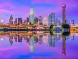 Dallas, Texas, USA downtown city skyline at night with the skyscrapers reflecting in the water in the foreground.