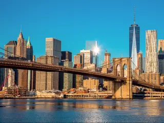 The Brooklyn Bridge with the early morning sunlight shining and some buildings on the background.
