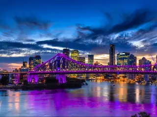 Brisbane, Australia with a vibrant night time panorama of Brisbane city with purple lights on Story Bridge.