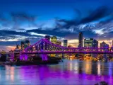 Brisbane, Australia with a vibrant night time panorama of Brisbane city with purple lights on Story Bridge.