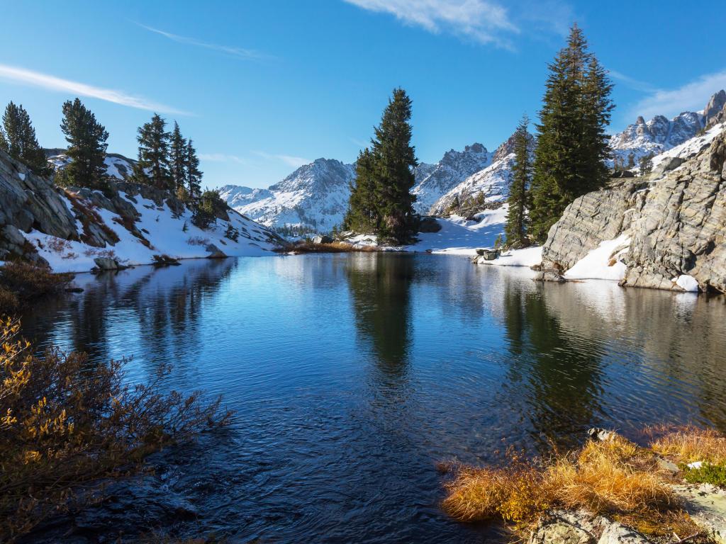 Sierra Nevada mountains, USA taken during winter with snow covering the mountains in the distance and a lake in the foreground. 