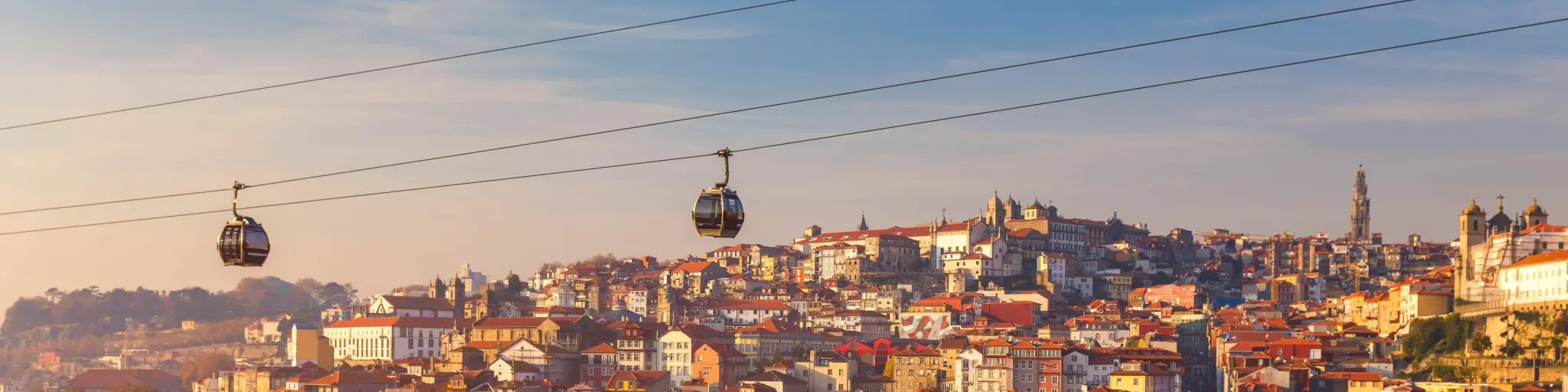 Colourful houses with red roof tiles in Porto, Portugal, with a cable car going overhead