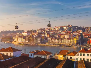 Colourful houses with red roof tiles in Porto, Portugal, with a cable car going overhead