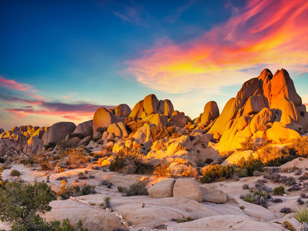 Pale coloured rocks lit up vibrant orange in sunset light with pink sky