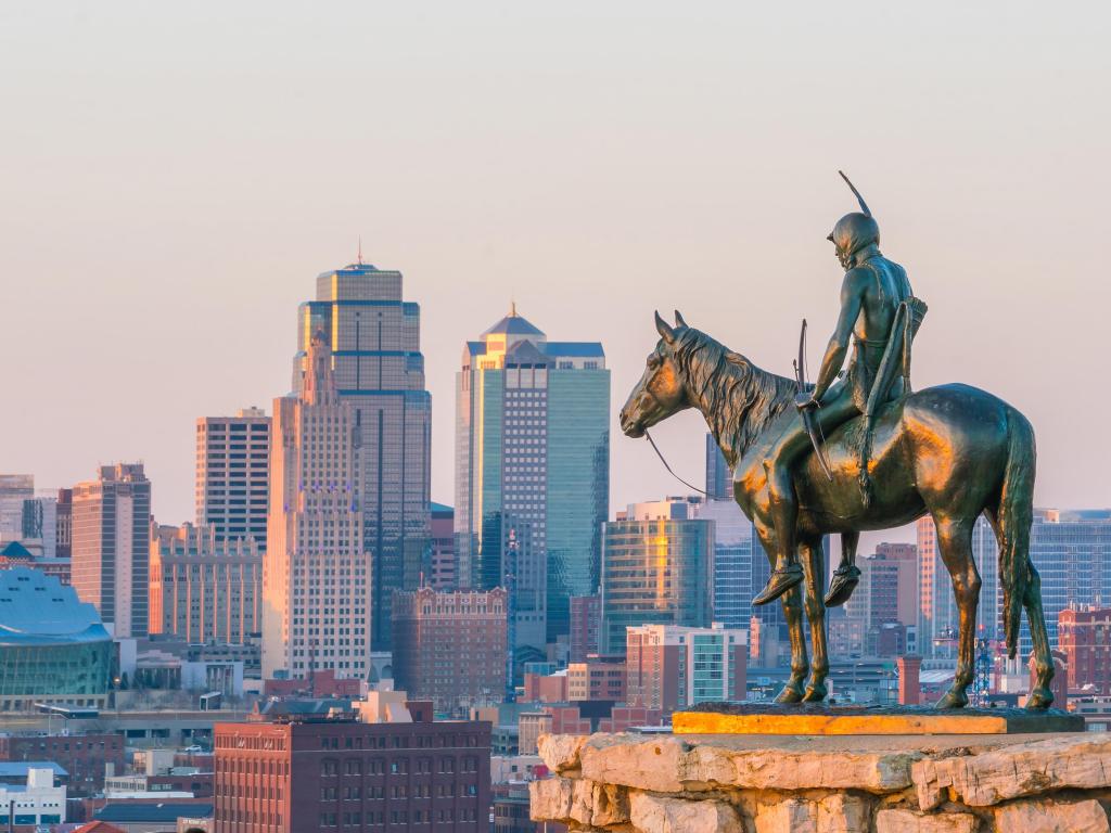 Kansas City, USA with the iconic Scout in the foreground overlooking downtown Kansas City in the background at sunset. 