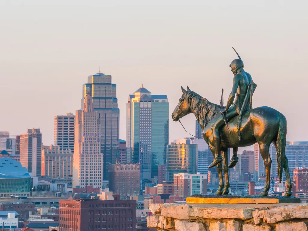 Kansas City, USA with the iconic Scout in the foreground overlooking downtown Kansas City in the background at sunset. 