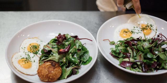 While plates topped with fried eggs and salad at Holybelly Cafe in Paris