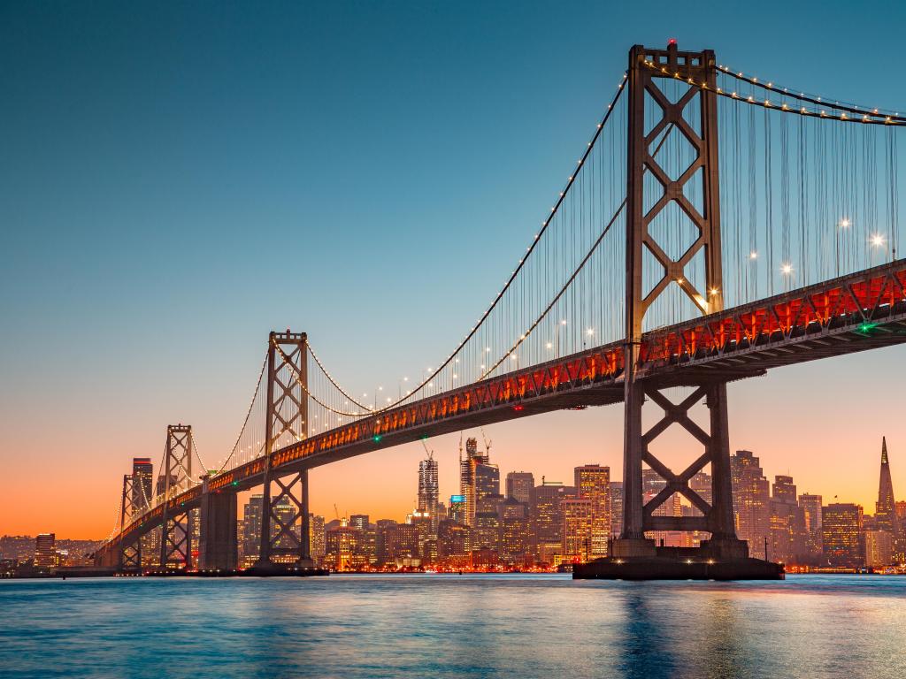 San Francisco Bay Area, California, USA taken from the famous Oakland Bay Bridge illuminated in beautiful golden evening light at sunset with the city skyline in the distance.